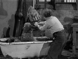 Moe covered in rubber, Curly and Larry help him out of the bathtub - Dizzy Pilots - Three Stooges